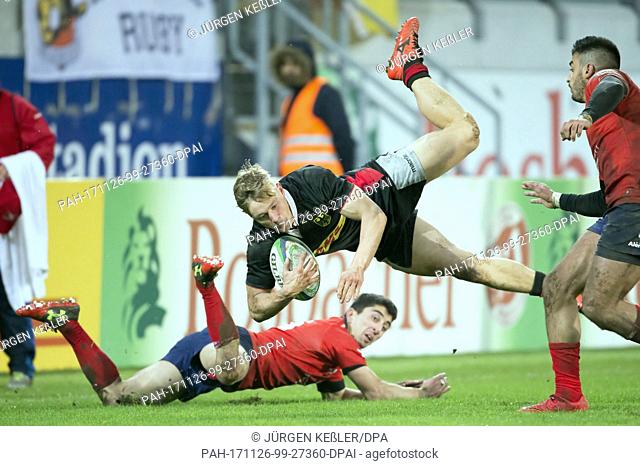 Chile's Tomas Ianiszewski (15), who lies on the ground, brings Germany's Tim Lichtenberg (14) down during the rugby international match between Germany and...