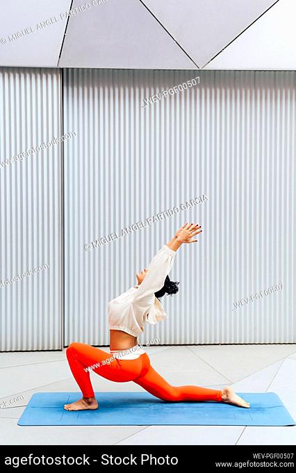 Female athlete doing backbend pose on exercise mat