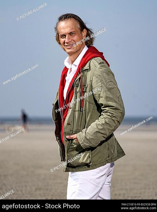 12 August 2021, Schleswig-Holstein, Sankt Peter-Ording: Actor Ralf Bauer stands on the beach of Sankt Peter-Ording in front of the waterline