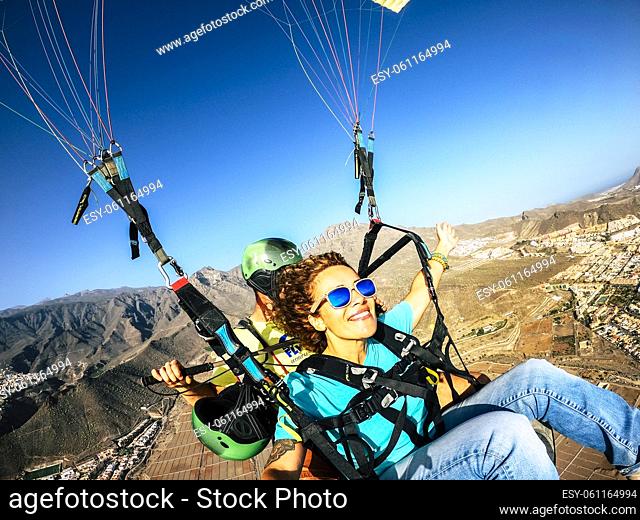 Happy tourist doing paragliding sport activity in outdoor leisure active lifestyle. Cheerful adult woman doing selfie picture flying on a paraglyde in summer...