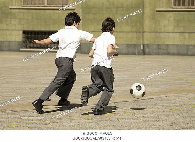 Young students playing soccer in courtyard