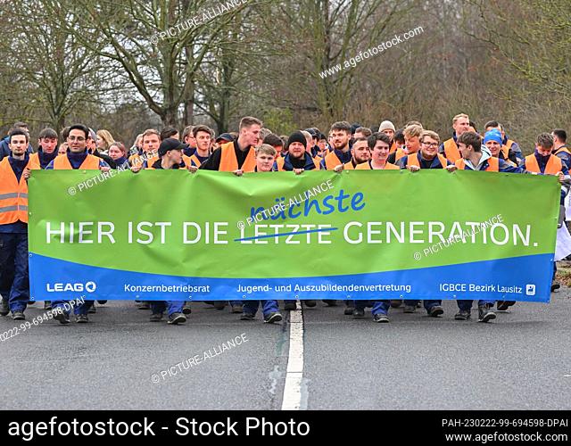 22 February 2023, Brandenburg, Spremberg: Protesting apprentices and employees from the energy company LEAG carry a banner reading ""Here is the next...