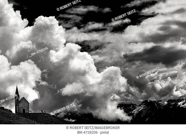 Latzfonser cross chapel with climber and dramatic clouds, monochrome, Sarntal Alps, San Martino, Sarntal, South Tyrol, Italy