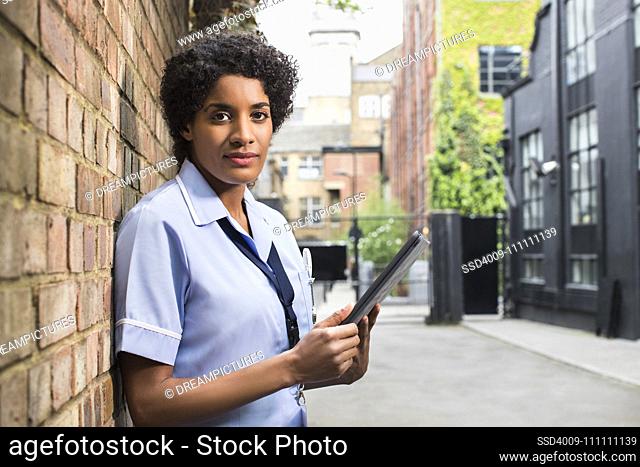 Portrait of Woman in healthcare industry standing in Alley using ipad