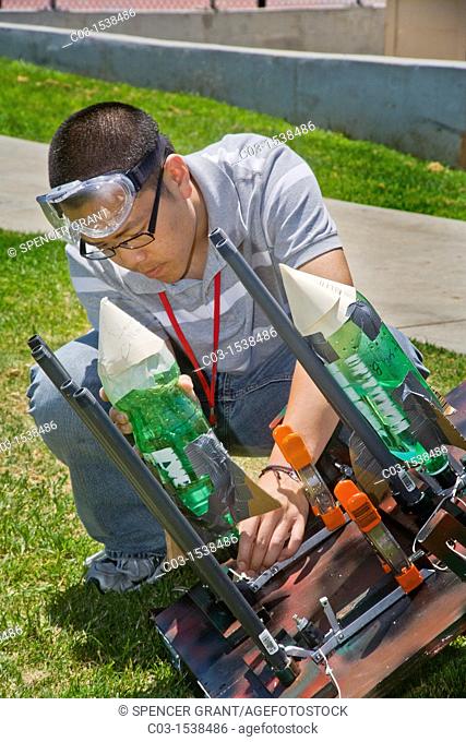 An Asian American teacher prepares to launch an air-and-water-powered bottle rocket as part of a high school summer science workshop at the University of...