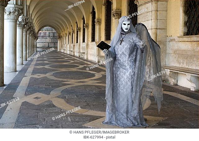Woman wearing angel costume during Carnival, standing in the arcade at Doge's Palace (Palazzo Ducale di Venezia), Venice, Veneto, Italy, Europe