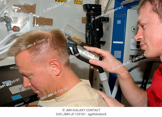 European Space Agency astronaut Frank De Winne (partially out of frame), Expedition 20 flight engineer, trims NASA astronaut Tim Kopra's hair in the Destiny...