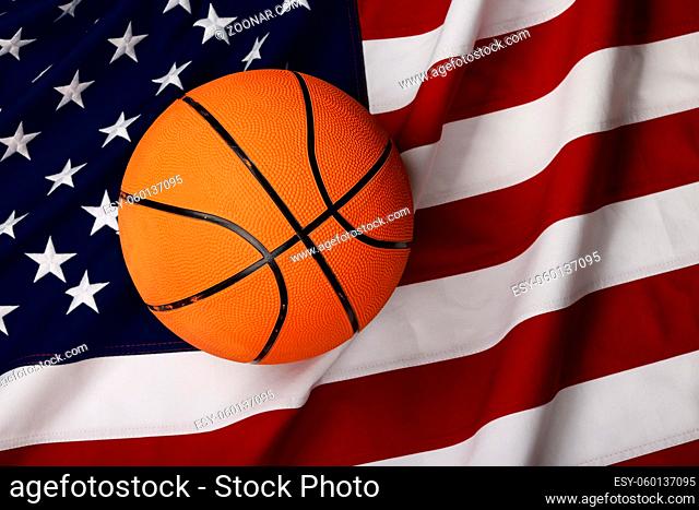 Close up worn orange basketball ball over American flag background, elevated top view, directly above