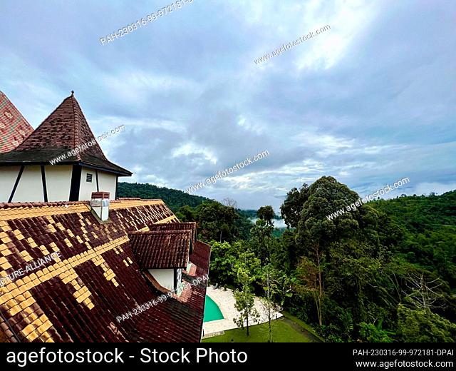 PRODUCTION - 02 March 2023, Malaysia, Colmar Tropicale: View over one of the gabled roofs of Colmar Tropicale to swaths of mist above the jungle of the Berjaya...