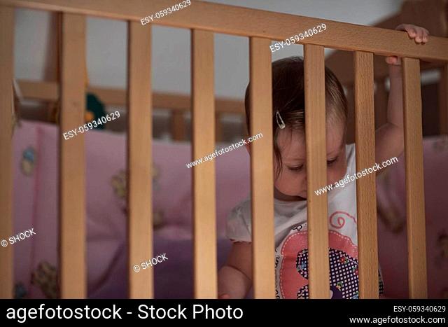 cute little one year old baby playing with toys in bed while making first steps and learnig to walk