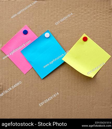 blank square sheets of paper stickers attached with an iron button on a brown cardboard surface. Design template