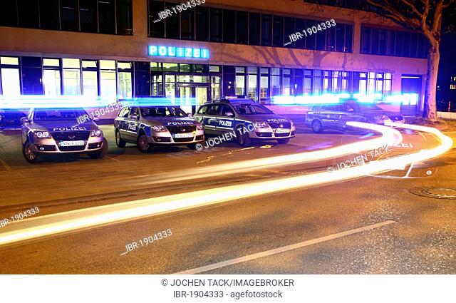 Police car driving off with flashing lights, patrol cars parked in front of a modern police station, Gelsenkirchen, North Rhine-Westphalia, Germany, Europe