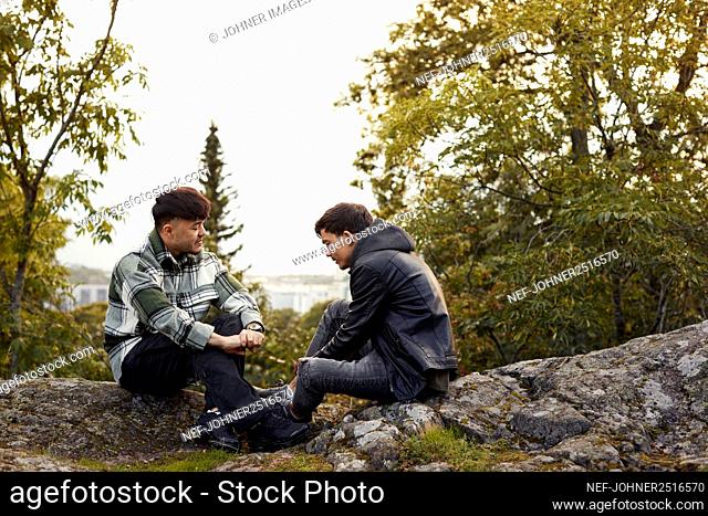 Young men sitting on rocks and talking