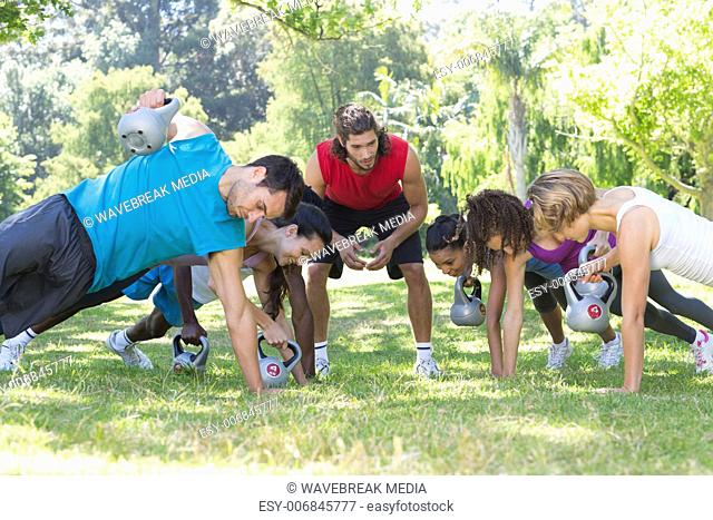 Fitness group planking in park with coach