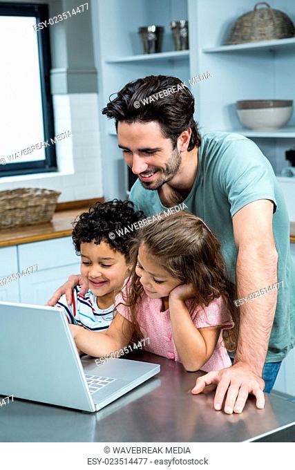 Smiling father using laptop with his children