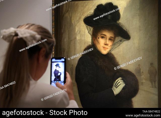 RUSSIA, MOSCOW - APRIL 17, 2023: A visitor takes pictures of a painting ""Russian Parisian woman"" (1891) by Leon Maxime Faivre at an exhibition titled 'After...