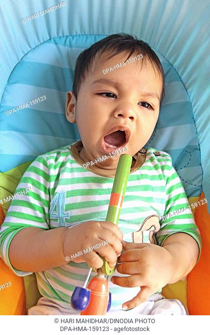 Baby boy yawning tired with wooden toy in hand MR732