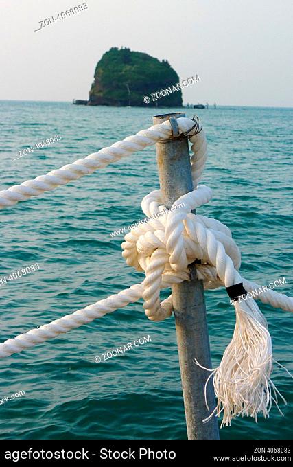 View of ropes on a seaboat with a small island as background