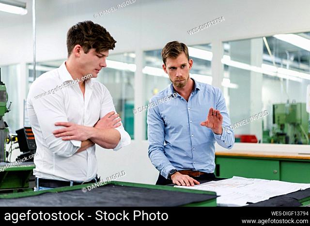Businessman explaining floor plan to male engineer while working in factory