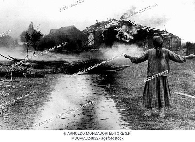 A Russian peasant woman's house burns. A Russian peasant woman watches her burning house on the southern front. August 1941