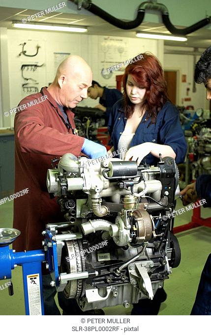 Teacher helping student with car engine