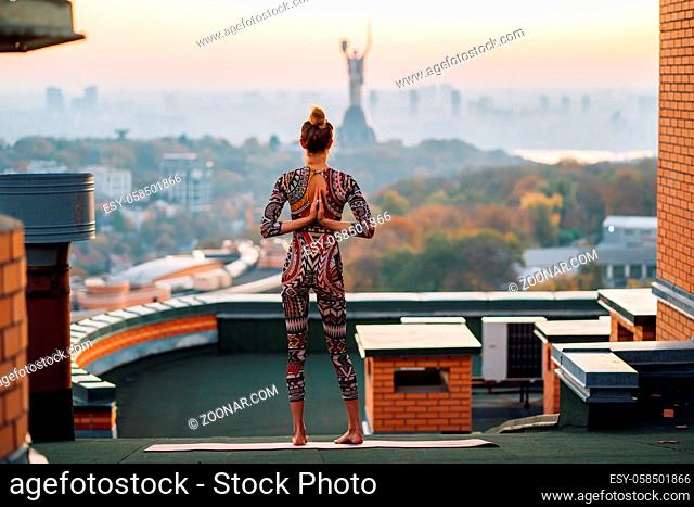 Woman doing yoga on the roof in big city