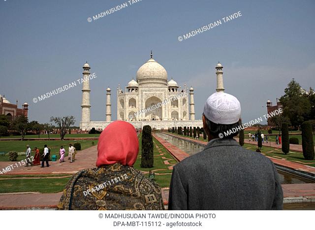 Kashmiri couple viewing at Taj Mahal Seventh Wonders of World on the south bank of Yamuna river , Agra , Uttar Pradesh , India UNESCO World Heritage Site