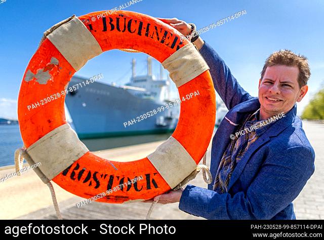 28 May 2023, Mecklenburg-Western Pomerania, Rostock: Filmmaker Merlin Franke holds an original life preserver of the cargo and passenger ship ""Georg Büchner""