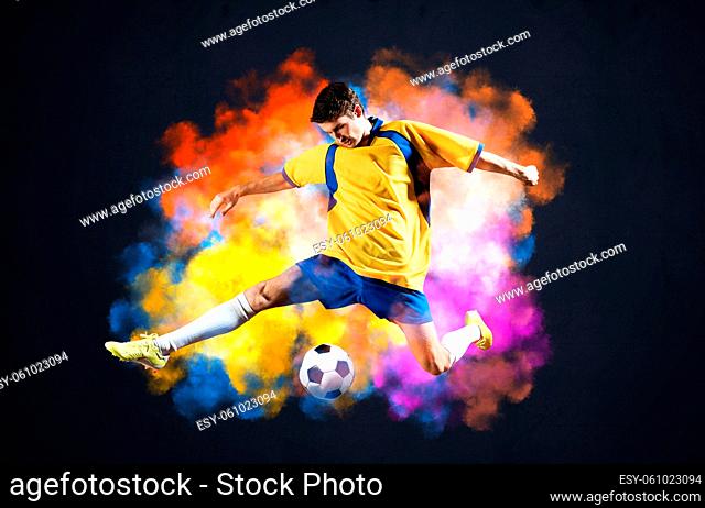 Soccer player kicking ball in colorful smoke. Sportsman in yellow and blue uniform in action. Soccer game championship concept with copy space