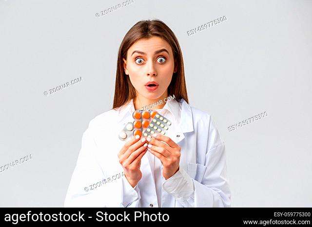 Pharmacy, healthcare workers, insurance and hospitals concept. Shocked or excited female doctor in white scrubs, pharmacist open mouth and gasping