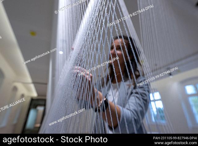 PRODUCTION - 03 November 2023, Saxony, Plauen: A woman looks at an installation made of threads in the new museum in the Weisbach House in Plauen