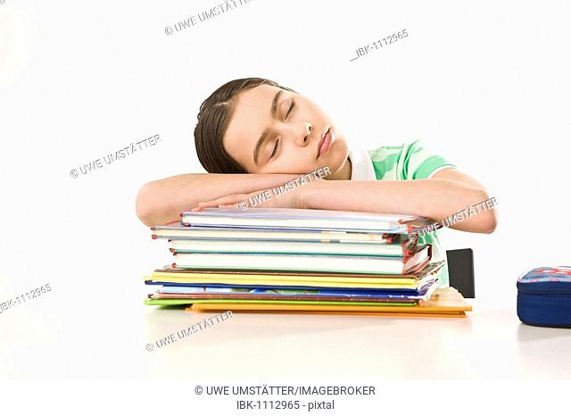 Girl sleeping on a pile of exercise books and school books