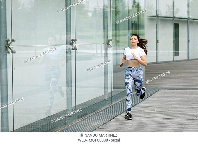 Young woman running along building in the city