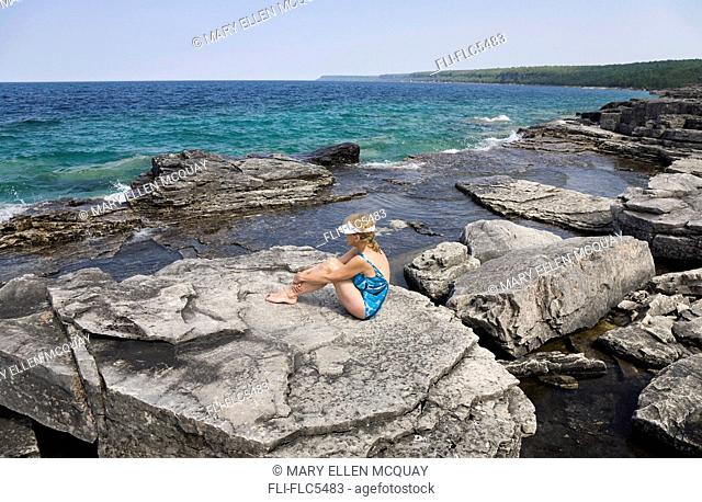 Woman sunbathing on a rocky beach, Bruce National Park, Georgian Bay, Ontario