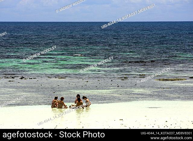 Young people cool off sitting in shallows Hat Sai Ri beach Ko Tao island Thailand