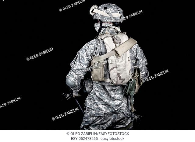 Back view of modern military forces infantry, US marine armed with rifle in digital camouflage combat uniform, protected helmet and body armour with hydration...