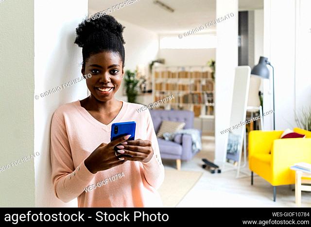 Happy woman doing shopping over mobile phone while standing at home