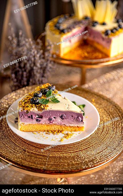Piece of blueberry cheesecake on white plate, ready to eat