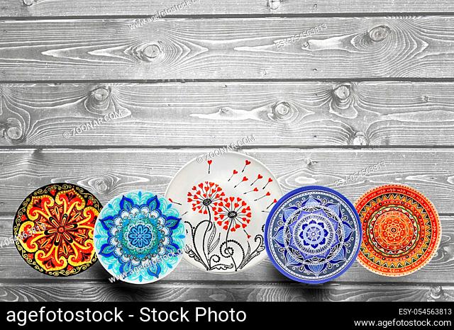 Set of decorative ceramic plates hand painted dot pattern with acrylic paints on a gray wooden background. Copy space