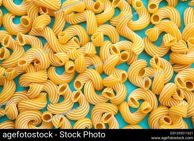 ellow background of pasta in the form of tubes spun in a spiral