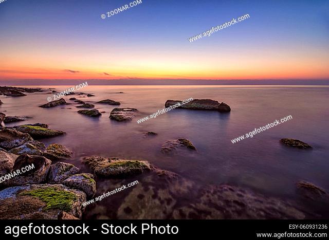 Relaxing long exposure seascape of rocky coast before sunrise