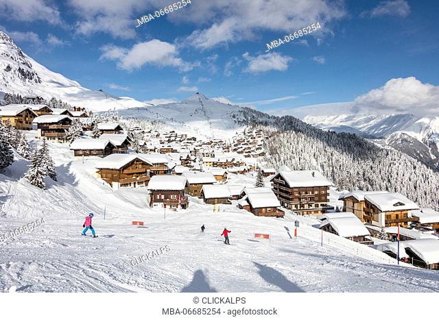 Skiers on the ski slopes frame the typical alpine village Bettmeralp district of Raron canton of Valais Switzerland Europe
