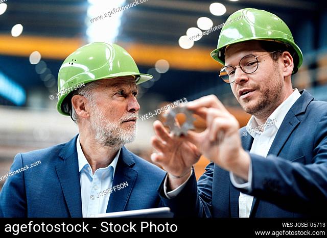 Male professional explaining equipment to manger in factory