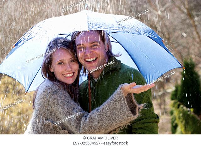 Young couple enjoying the rain under an umbrella