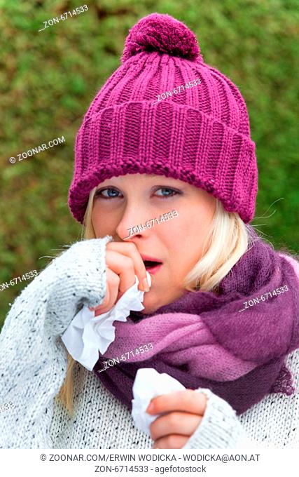 Eine junge Frau hat Schnupfen und ist erkältet. Herbstzeit ist Zeit für Grippe, Schnupfen und Erkältung