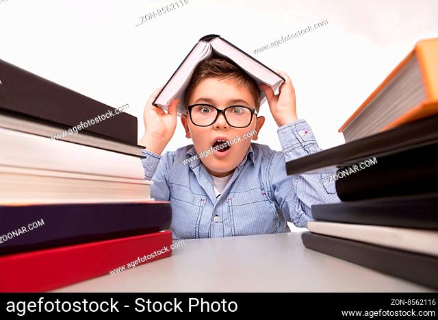 Close-up portrait of little business boy hiding from problems in the book and shouting. Man sitting among many books