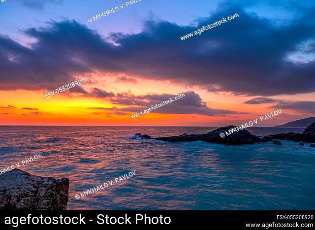 Rocky seashore. A lot of clouds in the sky and amazing colors until dawn