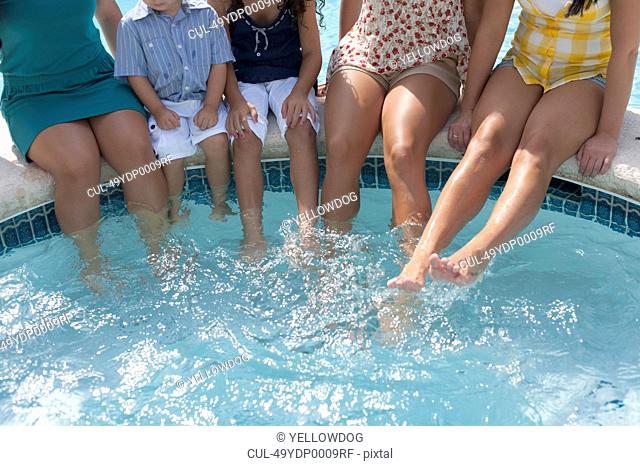 Family dangling feet in swimming pool