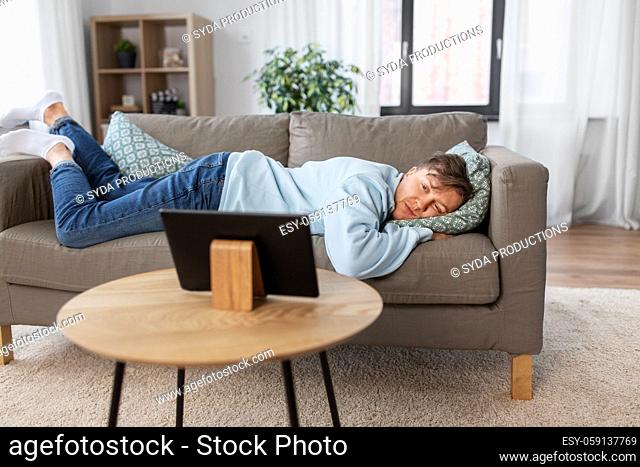 bored man with tablet pc lying on sofa at home