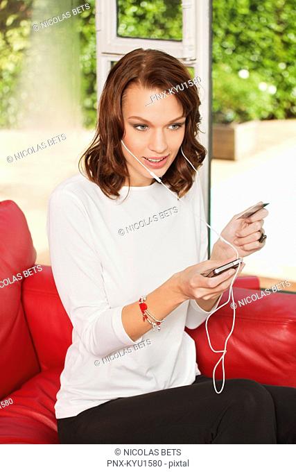 Young woman using iPhone, holding credit card